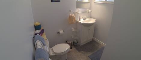 A compact bathroom with a toilet, sink, and a small shelf.