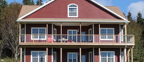 A two-story house with a balcony, large windows, and a red exterior.