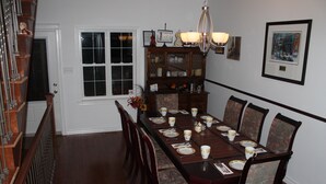 Comedor con una larga mesa de madera dispuesta para seis personas, rodeada de sillas con tapicería estampada.