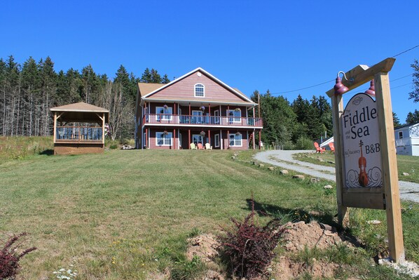 A two-story building with a balcony and a sign indicating 'The Fiddle and the Sea' with a 'No Vacancy' notice. - The Fiddle and The Sea B&B (Port Hood)