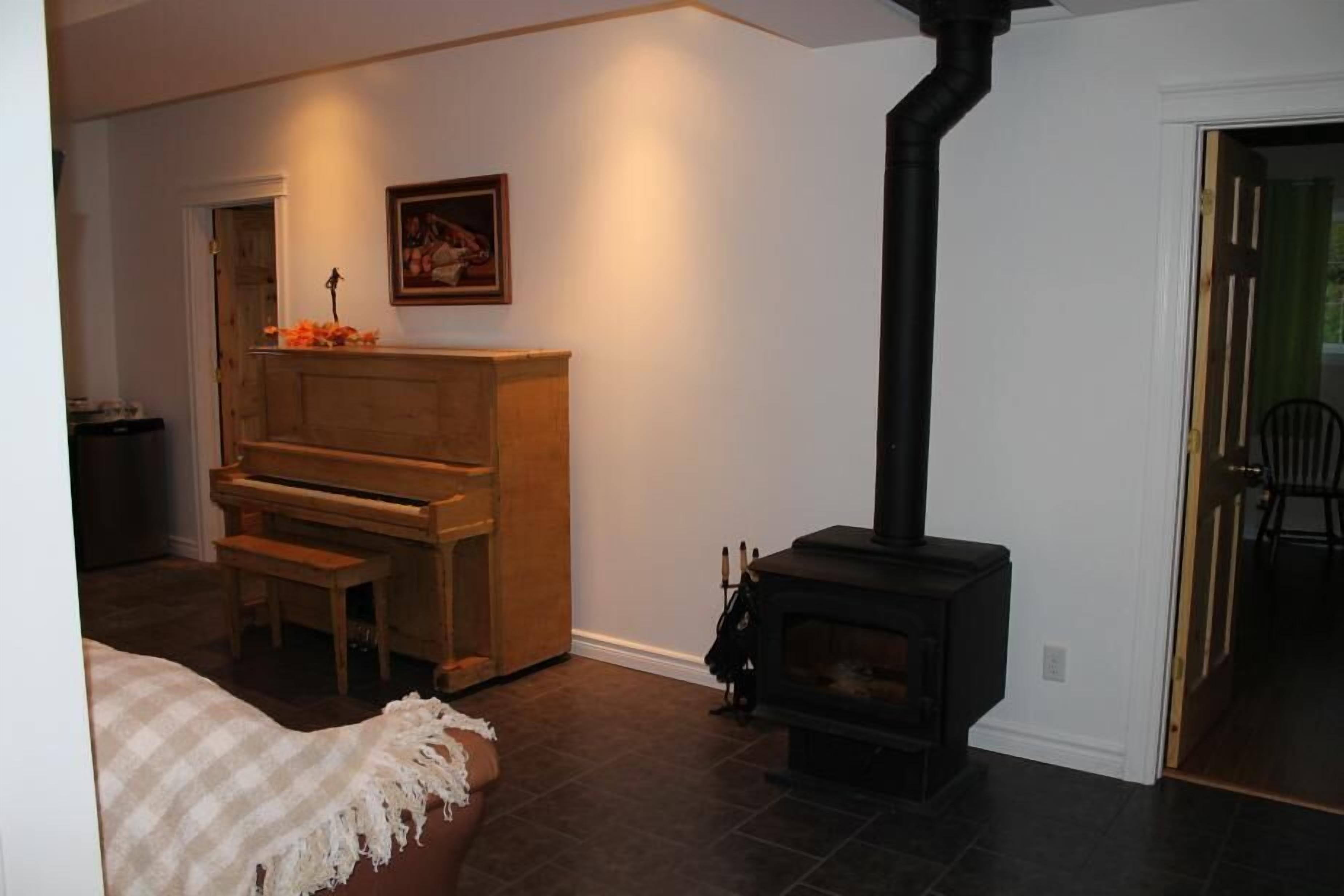 A cozy living room with a piano, a fireplace, and a door leading to another room.