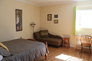 A bedroom with a bed, a sofa, a chair, a lamp, and a window with curtains. - The Fiddle and The Sea B&B (Port Hood)
