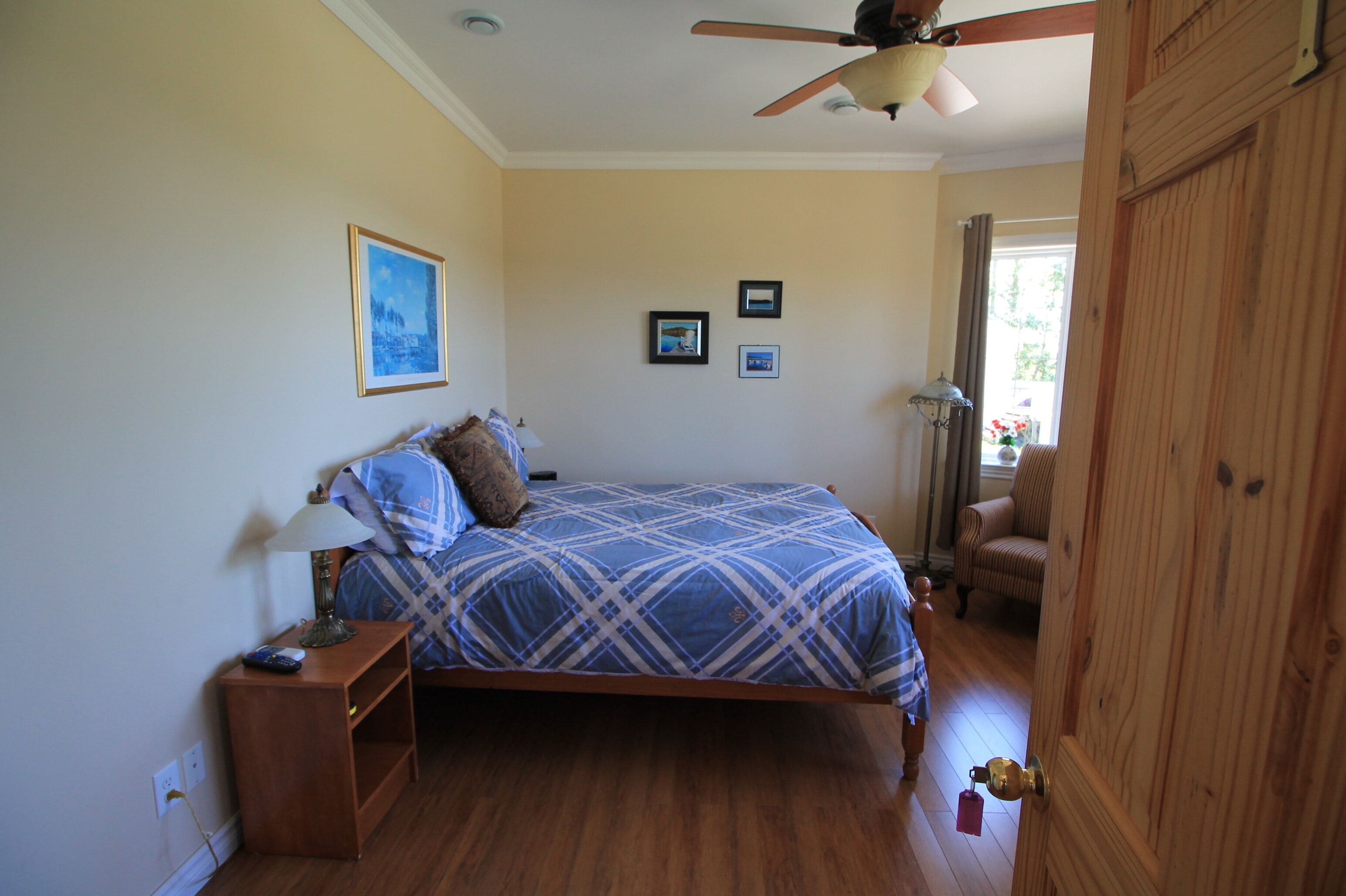 Une chambre à coucher avec un lit, une table de chevet, un ventilateur de plafond et une porte.