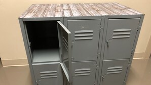 A metal locker with a wooden top, featuring multiple compartments and a sliding door. - SLC Hostel (Salt Lake City)
