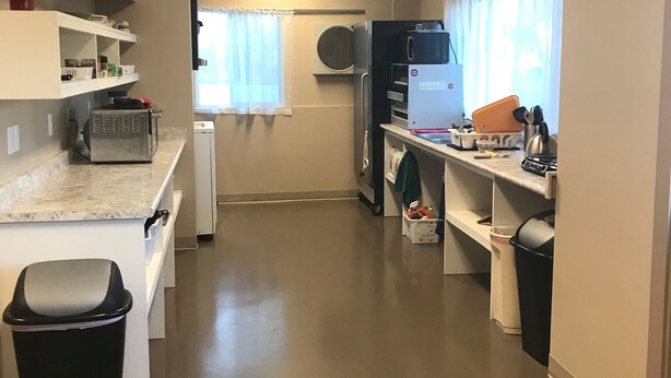 A compact kitchen with white cabinets, a microwave, and a small countertop. - SLC Hostel (Salt Lake City)