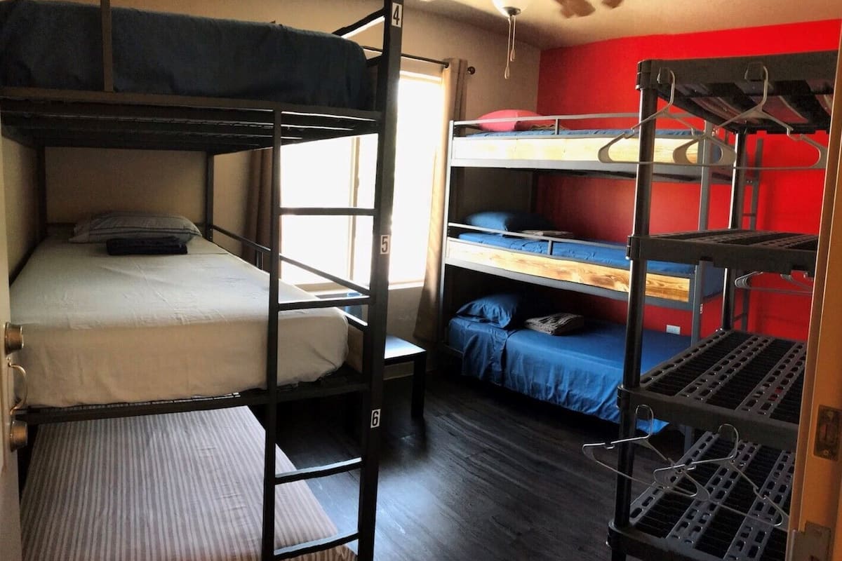 A dormitory room with bunk beds, numbered from 4 to 6, and a window providing natural light.