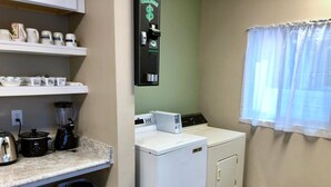 A laundry room with a washing machine, a coffee maker, and a kettle on the counter. - SLC Hostel (Salt Lake City)