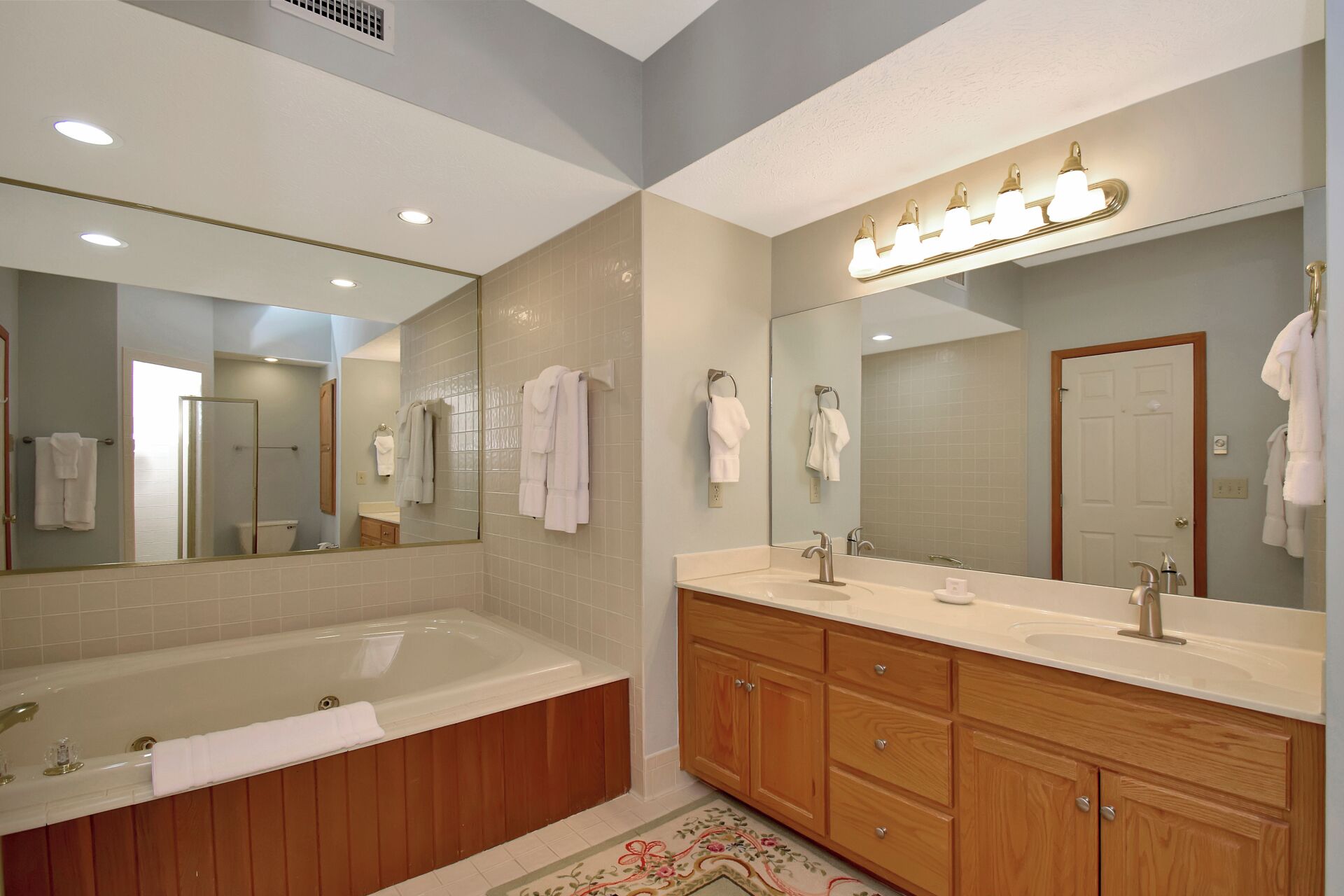 A modern bathroom with a bathtub, a vanity with a sink, a large mirror, and a shower.