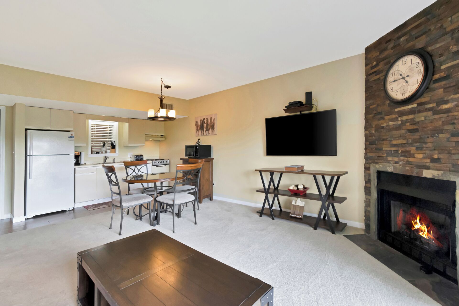 A living room with a fireplace, a dining area, and a kitchen in the background.