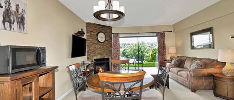 A living room with a fireplace, a dining area, a sofa, and a television.