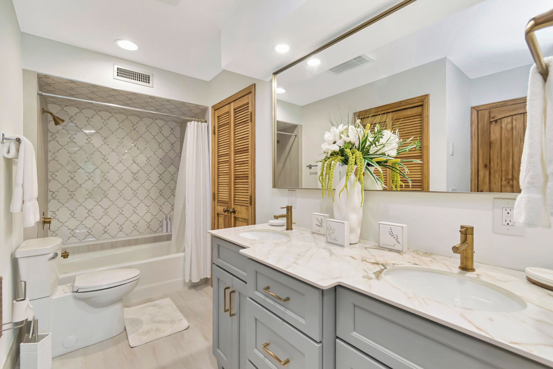 A modern bathroom with a bathtub, toilet, and two sinks.