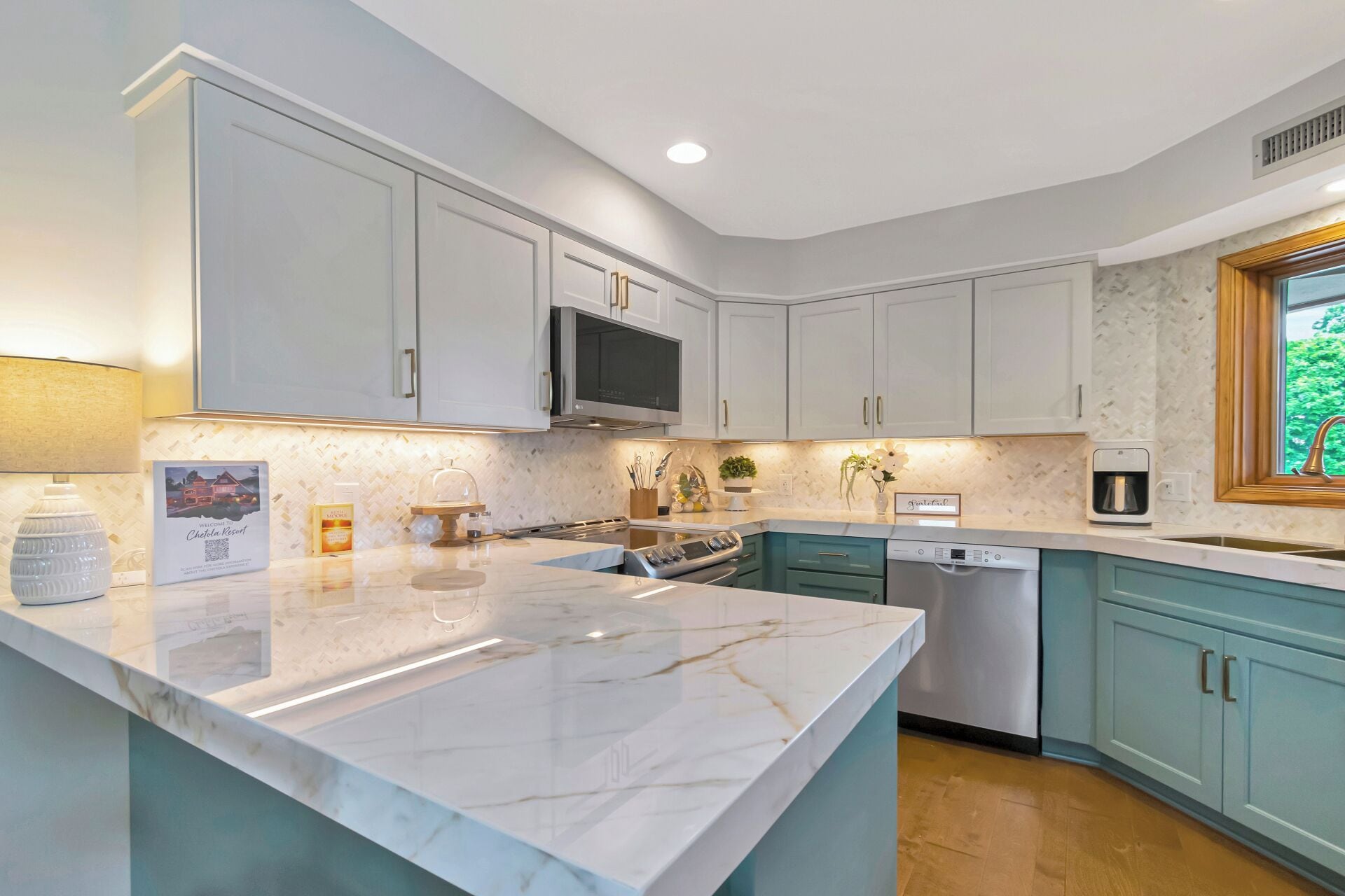A modern kitchen with white cabinets, a marble countertop, and a built-in dishwasher.