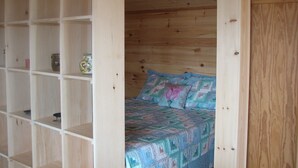 A wooden room with a bed, shelves, and a small table. - Cape Split View Cottages (West Bay)