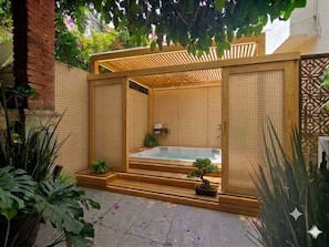 A spa area with a hot tub, wooden pergola, and bamboo screens.