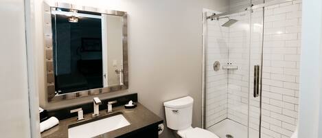 A modern bathroom with a sink, toilet, and glass-enclosed shower.