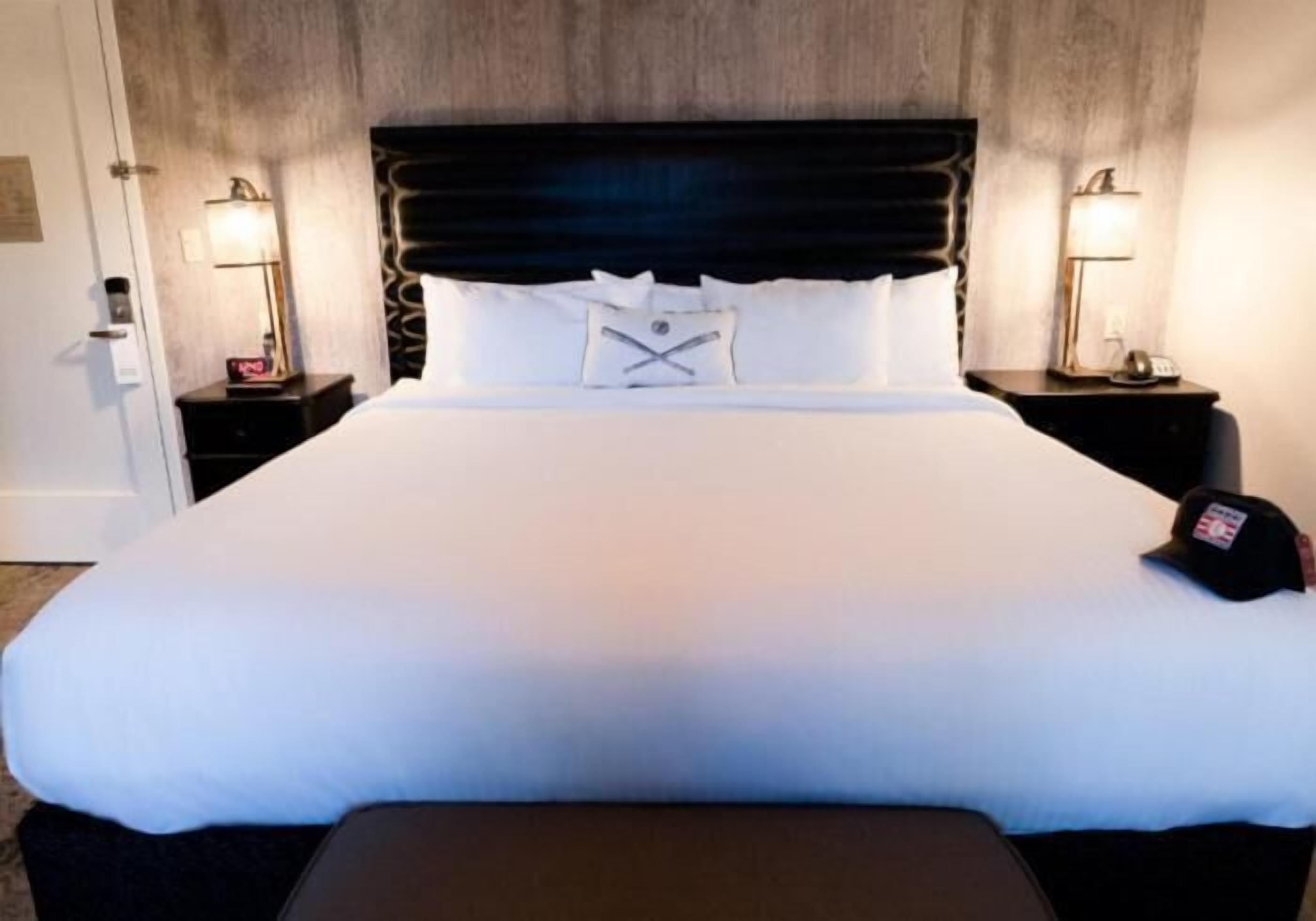 Una habitación de hotel con una cama grande, dos mesitas de noche y una mesilla.