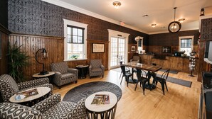 A spacious living room with patterned furniture, a dining area, and a kitchen with wooden cabinets. - The Railroad Inn (Cooperstown)