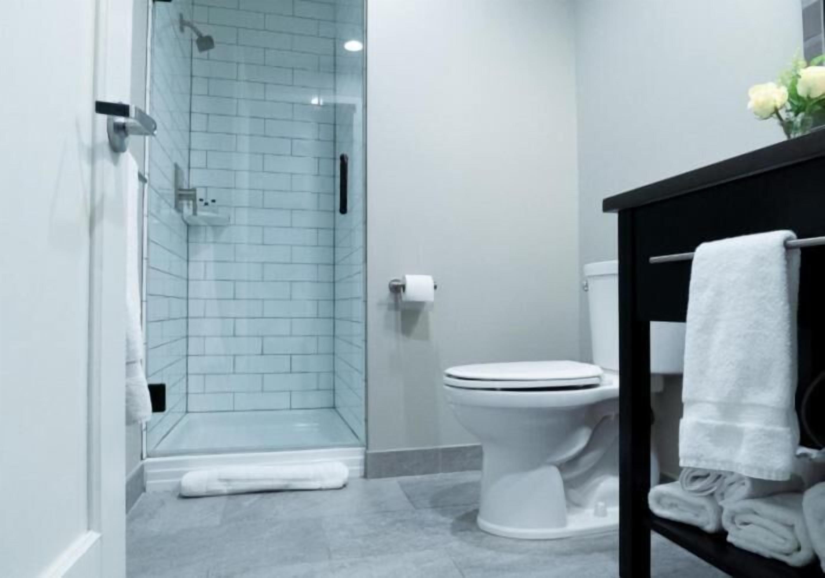 A modern bathroom with a glass-enclosed shower, a white toilet, and a black vanity with a towel rack.