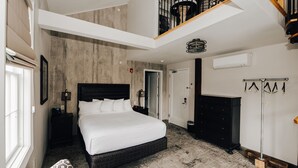 A modern bedroom with a large bed, a wooden ceiling, and a staircase. - The Railroad Inn (Cooperstown)
