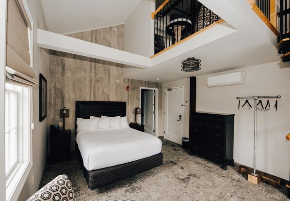Un dormitorio moderno con una cama grande, techo de madera y una escalera.