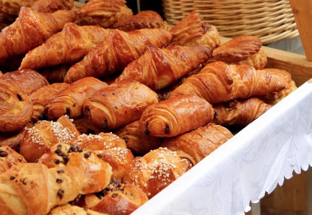A variety of pastries, including croissants and chocolate-filled rolls, displayed in a basket.