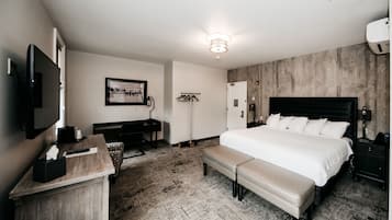 Une chambre d’hôtel avec un grand lit, un bureau, une télévision et une armoire.