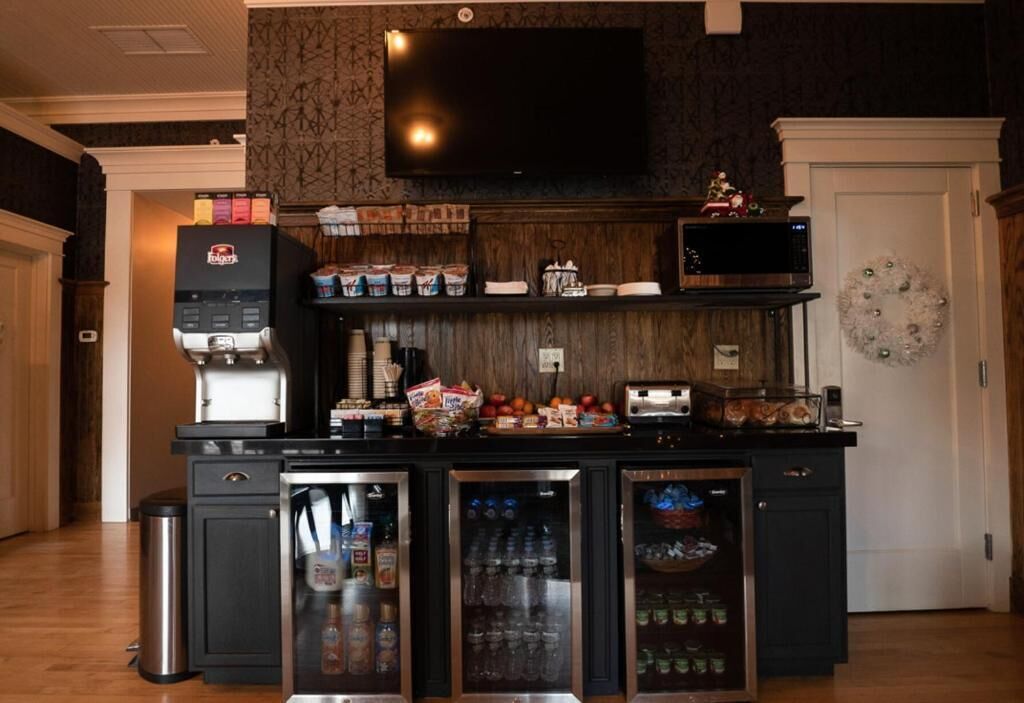 A kitchen with a built-in microwave, toaster, and refrigerator. There are cabinets with various items and a trash can.