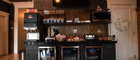 A kitchen with a built-in microwave, toaster, and refrigerator. There are cabinets with various items and a trash can.