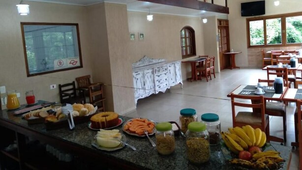 A breakfast buffet with various food items and a seating area with tables and chairs. - Hotel Vill' Agi (Campos do Jordão)
