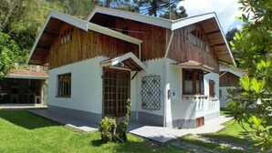 A two-story house with a sloped roof, wooden exterior, and a small front porch.