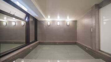 A spacious, well-lit indoor area with tiled floors and walls, featuring a large window on one side and wall-mounted lighting.