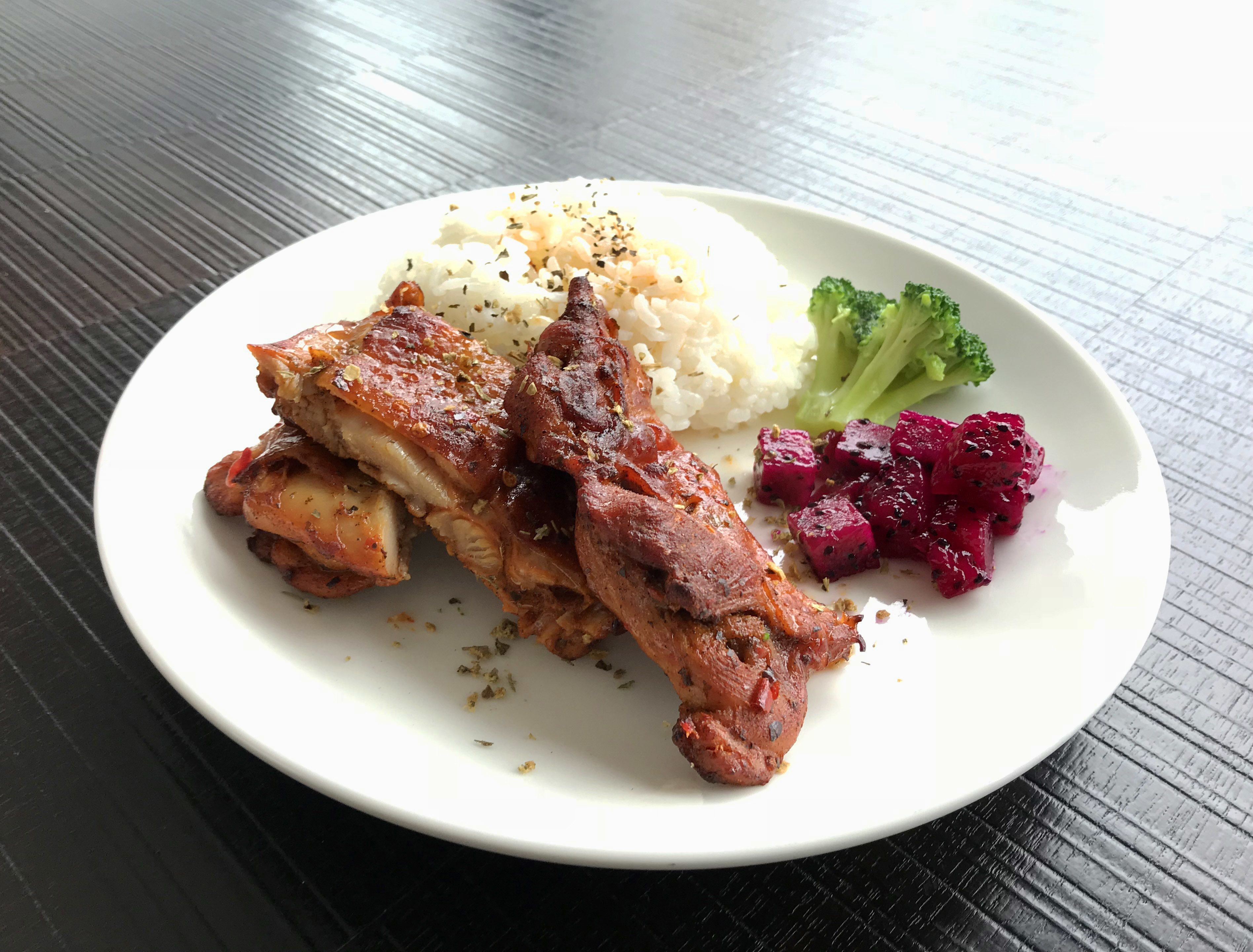 A plate with roasted meat, rice, broccoli, and beetroot.