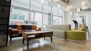 A modern interior with a colorful sofa, a wooden coffee table, and a green ottoman. - Single Inn Kaohsiung Station Hostel (Kaohsiung)