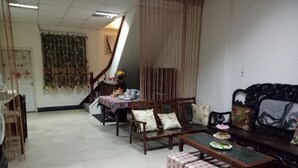 A living room with a sofa, a coffee table, and a dining table. There is a staircase leading to another room. - Tainan Here Hostel (Tainan)