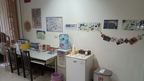 A small office with a desk, chairs, a water dispenser, a refrigerator, and various photos and notices on the wall. - Tainan Here Hostel (Tainan)