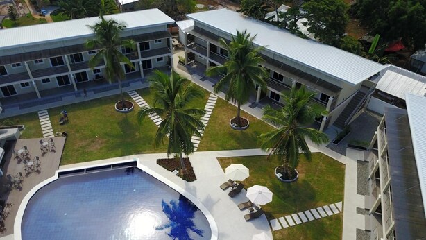 Un hôtel moderne doté d’une piscine centrale, d’un espace extérieur aménagé et de palmiers.