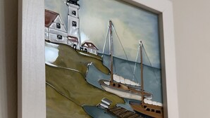 A framed painting of a harbor scene with boats, a lighthouse, and buildings. - Tainan Here Hostel 2 (Tainan)