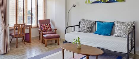 A modern living room with a sofa, armchairs, a coffee table, and a painting on the wall.