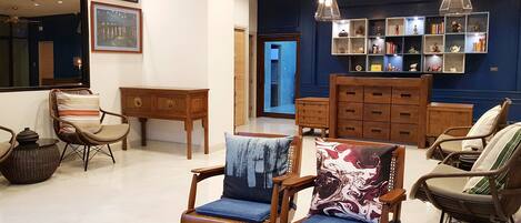 A spacious living room with a high ceiling, wooden furniture, and a bookshelf filled with books and decorative items.