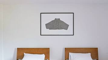 Two single beds with wooden headboards and white linens, a framed picture on the wall, and a wooden floor.
