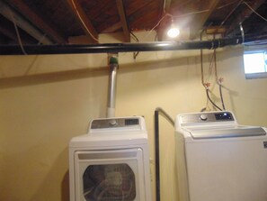 A laundry room with two stacked washers and dryers, a visible ductwork, and a window with a view. - Just You Vacation Home (Gilbert Plains)