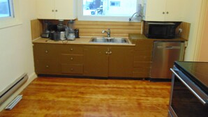 A compact kitchen with a sink, microwave, and dishwasher. - Just You Vacation Home (Gilbert Plains)