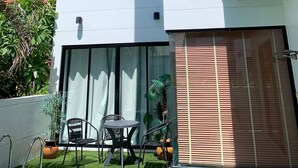A modern two-story house with large windows, a flat roof, and a small patio area with chairs and a table. - 3 Bedroom Villa SDV261- Walk to Beach-By Samui Dream Villas (Koh Samui)