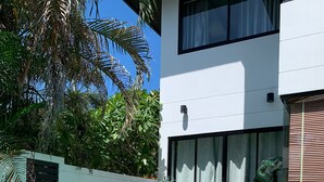 A swimming pool with clear water, surrounded by a white building with large windows and a tiled deck. - 3 Bedroom Villa SDV261- Walk to Beach-By Samui Dream Villas (Koh Samui)