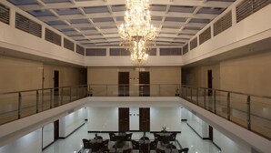 A spacious, modern hotel lobby with a high ceiling, a central chandelier, and a glass railing overlooking a dining area. - One El Nido Suite (El Nido)