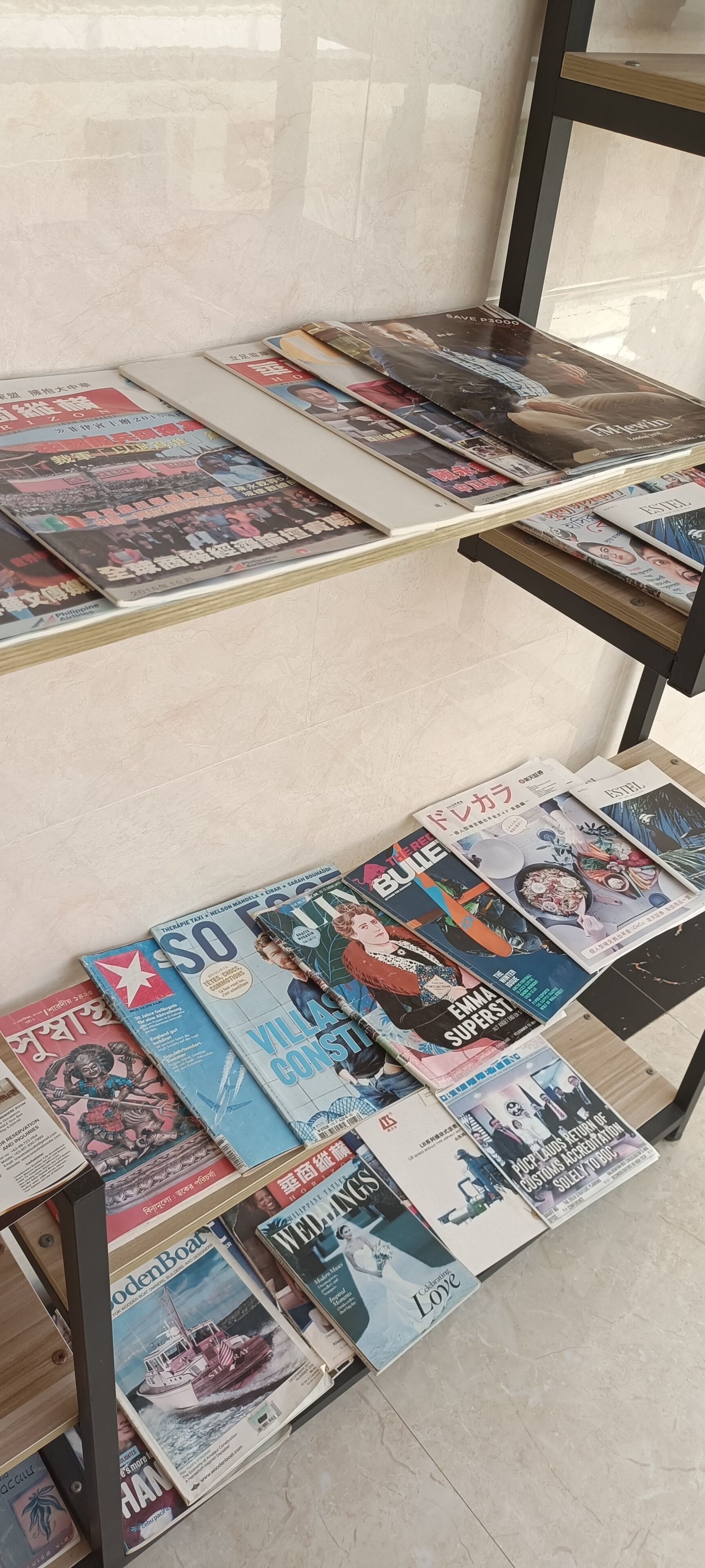 Varias portadas de revista exhibidas sobre mesas en una habitación con suelo de baldosas.