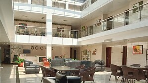A spacious atrium with a high ceiling, multiple seating areas, and a central staircase. - One El Nido Suite (El Nido)