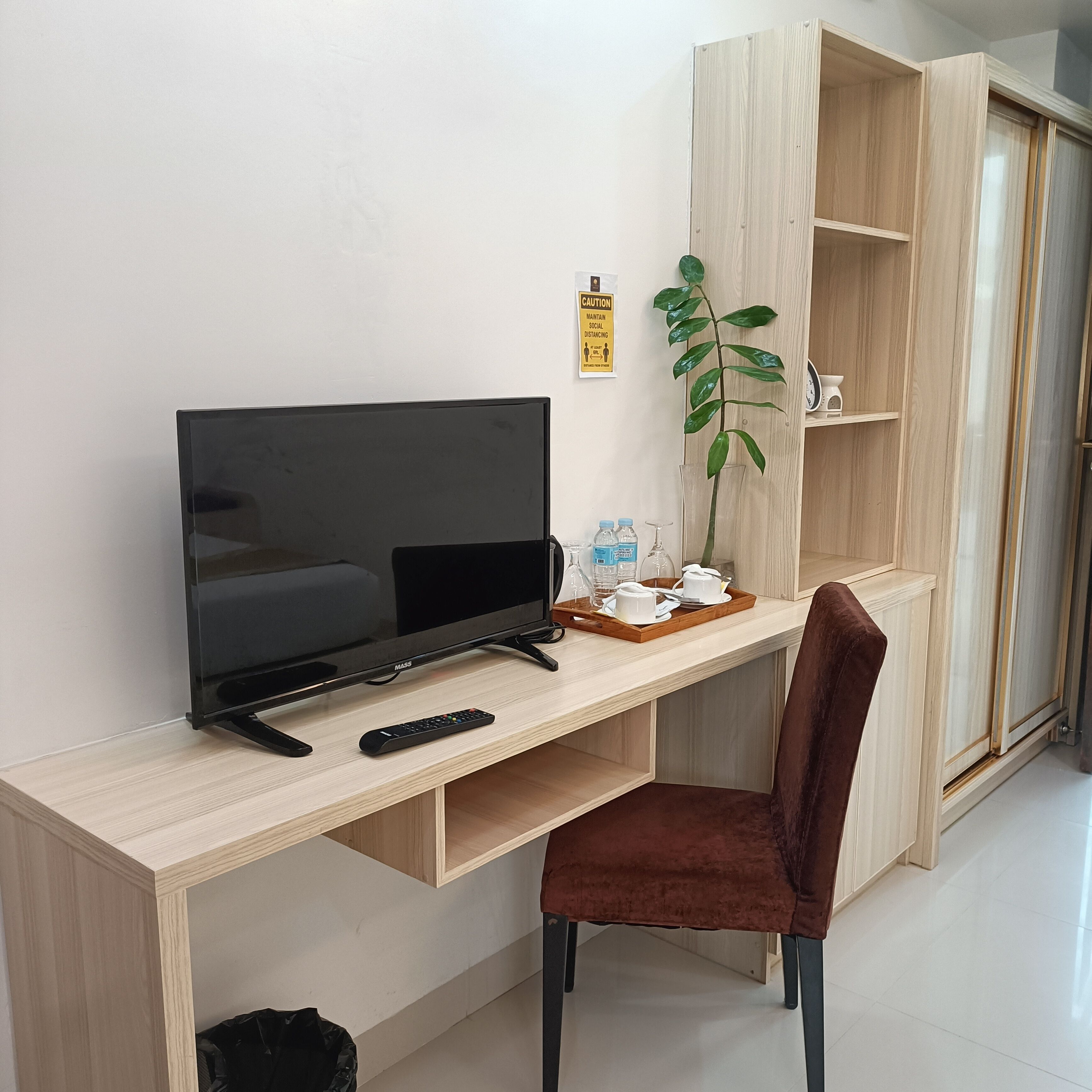 A modern room with a wooden desk, a television, a remote control, and a brown chair.