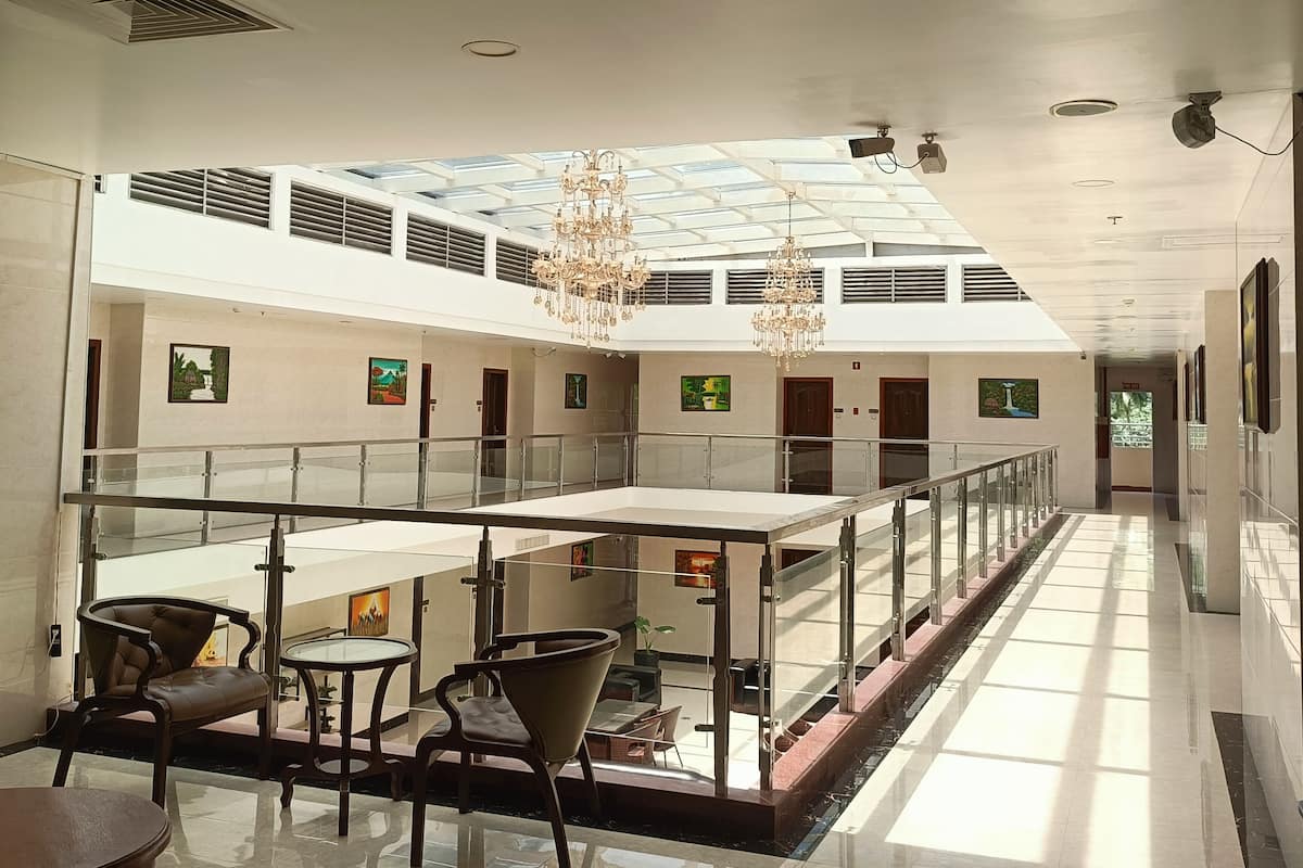 Um amplo hall de hotel com teto alto, um átrio de vidro e um mezanino.