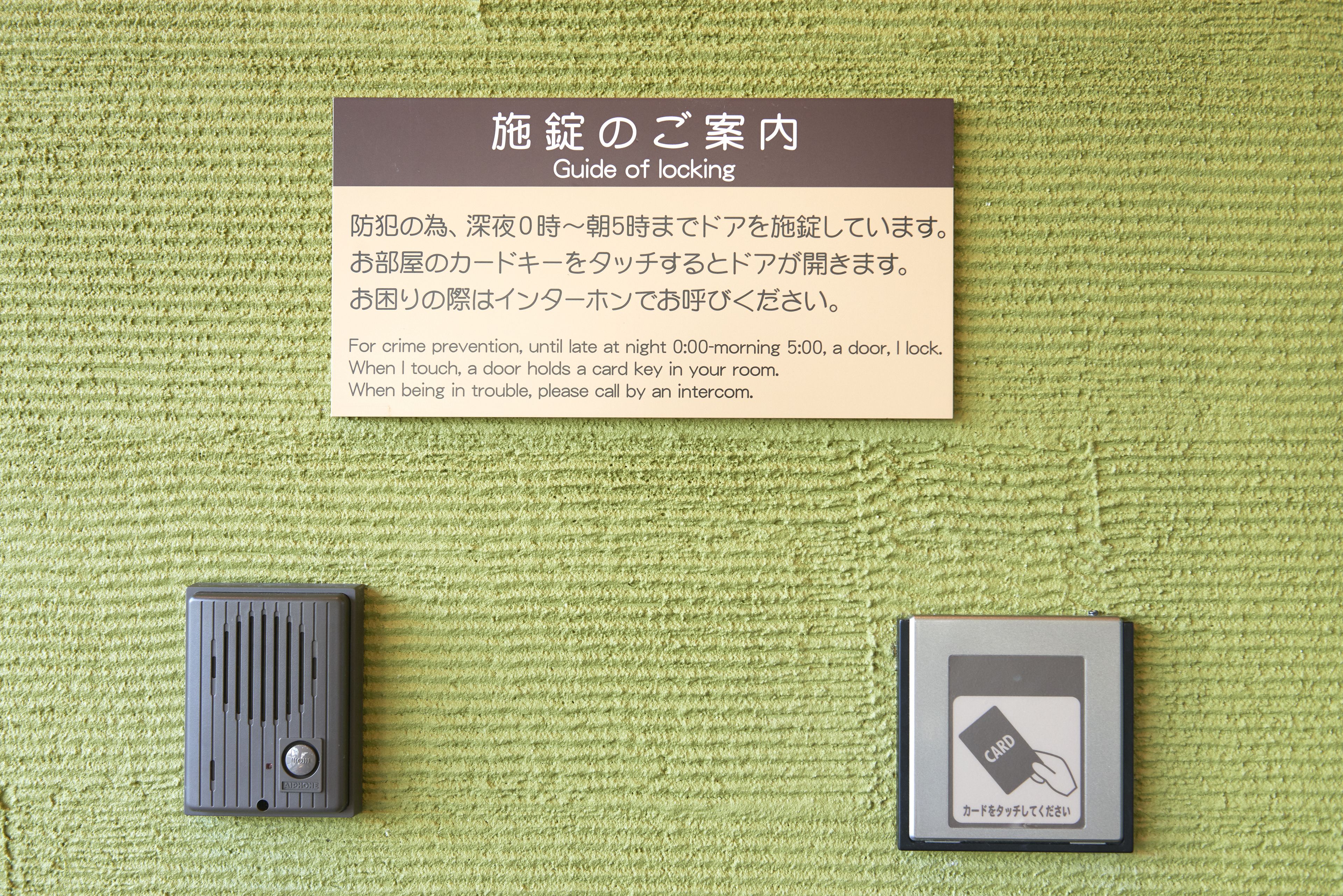 A guide of locking instructions on a green textured wall, a door lock, and a card reader.